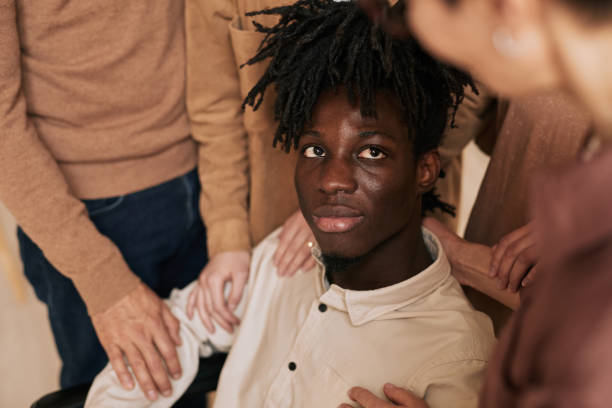Close up of people comforting young man in wheelchair during therapy session in support group, copy space