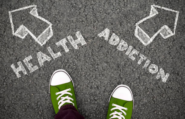 Health Or Addiction, Two Opposite Ways. Top view of feet with chalk drawing on the asphalt road