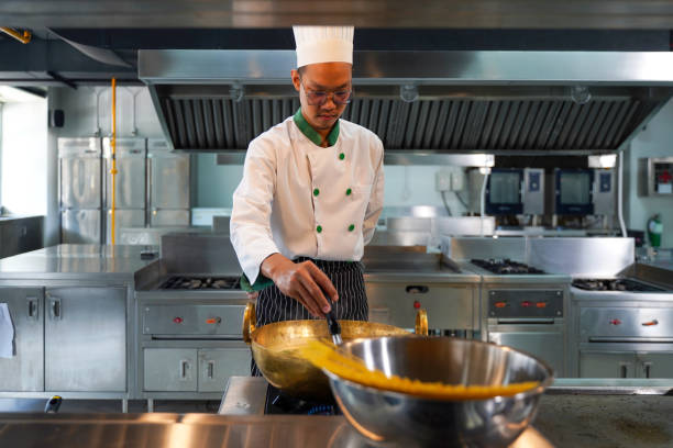 Chef man cooking food in class kitchen room.  Chef preparing student for learning marking and cooking food at workshop.  Education Concept