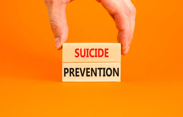Suicide prevention symbol. Concept words Suicide prevention on wooden blocks. Beautiful orange table orange background. Psychologist hand. Psychological and suicide prevention concept. Copy space.